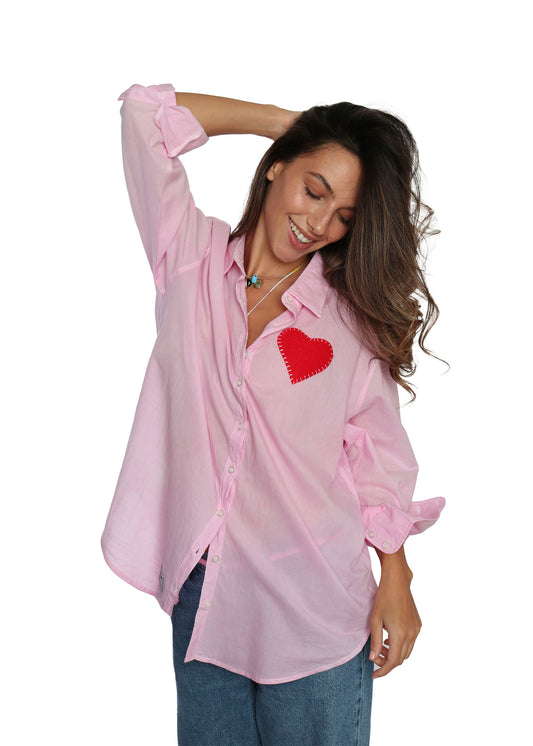 Woman wearing a pink shirt with a red heart design on a white background